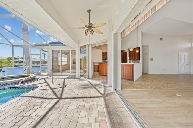 view of swimming pool featuring ceiling fan and a water view