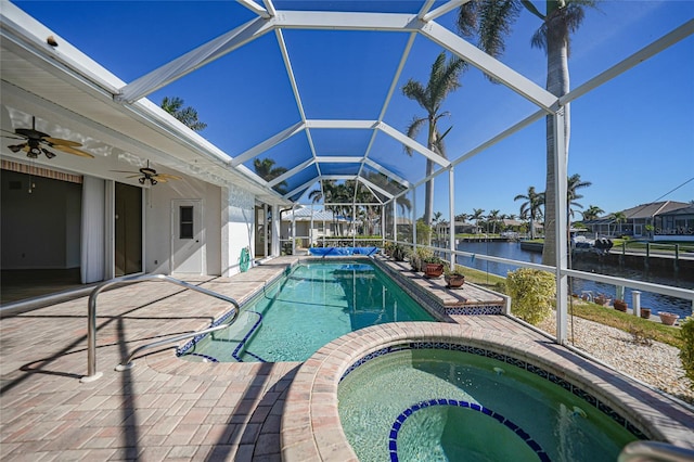 view of swimming pool featuring glass enclosure, a patio area, a water view, and an in ground hot tub