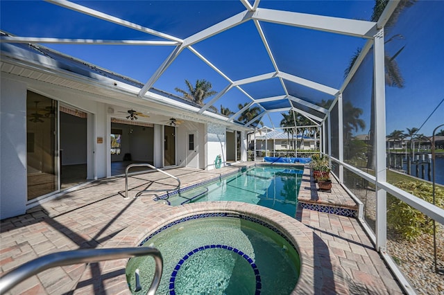 view of pool featuring ceiling fan, a lanai, an in ground hot tub, a water view, and a patio