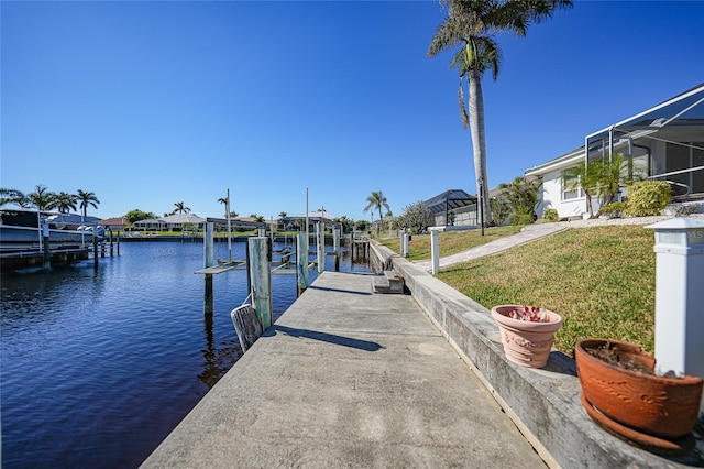 dock area with a lawn, glass enclosure, and a water view