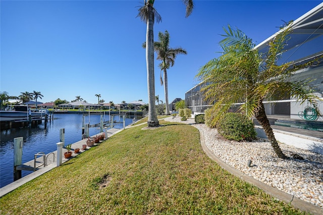 dock area with a lawn, glass enclosure, and a water view