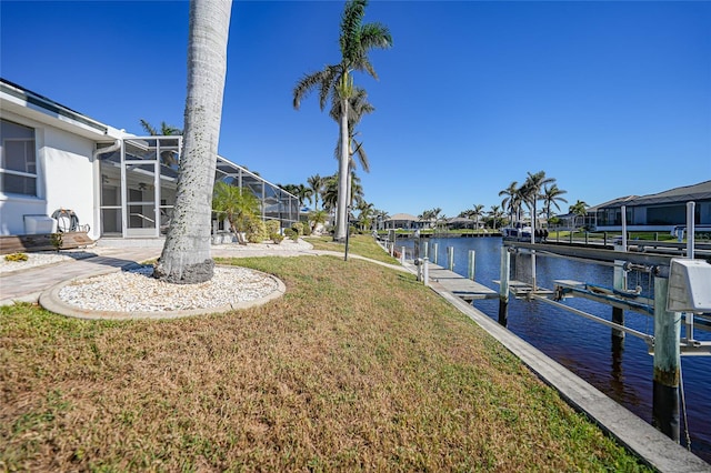 view of yard featuring a lanai, a water view, and a boat dock