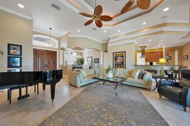 living room with ceiling fan with notable chandelier, ornamental molding, a high ceiling, and decorative columns