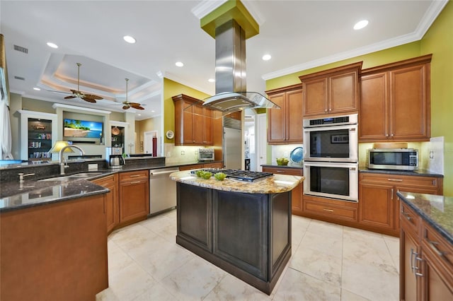 kitchen featuring island range hood, ornamental molding, appliances with stainless steel finishes, and dark stone counters