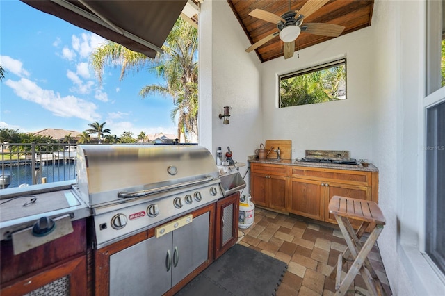 view of patio with a grill, a dock, a water view, and exterior kitchen