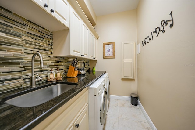 clothes washing area featuring washing machine and clothes dryer, sink, and cabinets