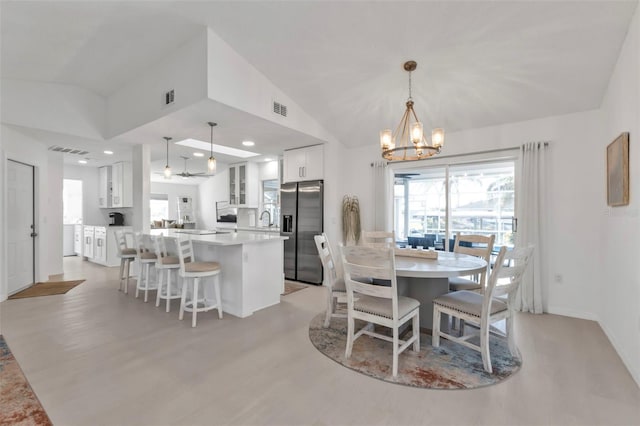 dining room featuring light wood-type flooring, lofted ceiling, sink, and a chandelier