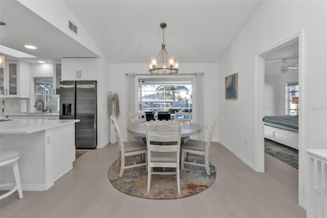 dining area with light hardwood / wood-style floors, lofted ceiling, and sink