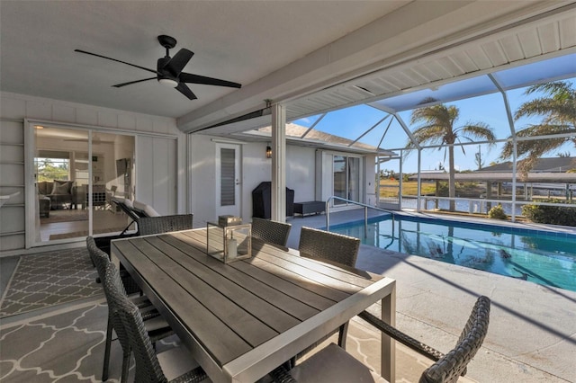 view of pool featuring glass enclosure, ceiling fan, a water view, and a patio