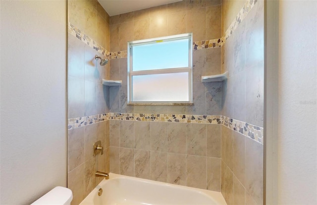 bathroom with tiled shower / bath combo and toilet