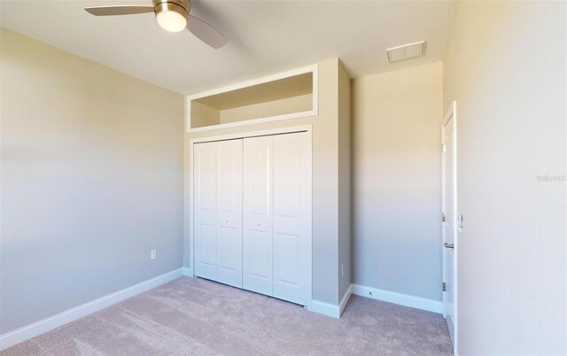 unfurnished bedroom with ceiling fan, a closet, and light carpet