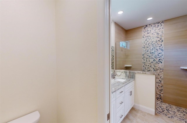 bathroom featuring vanity, toilet, and tiled shower