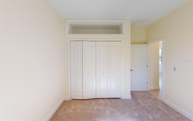 unfurnished bedroom featuring light colored carpet and a closet