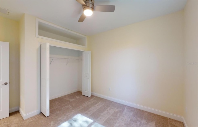 unfurnished bedroom featuring ceiling fan, a closet, and light colored carpet