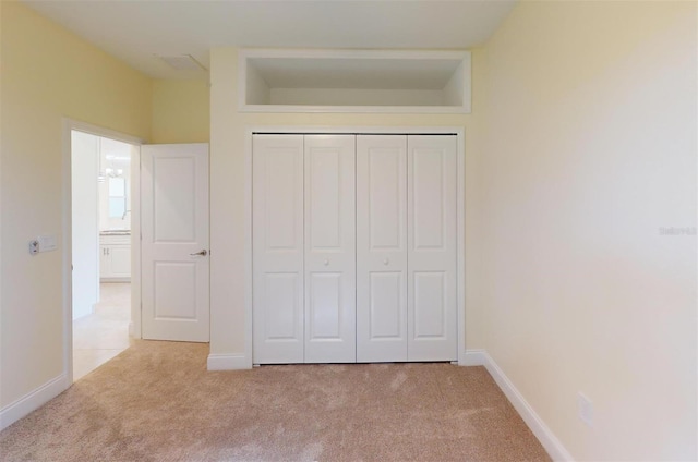 unfurnished bedroom featuring light carpet and a closet