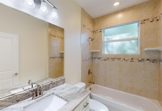 full bathroom featuring vanity, tiled shower / bath combo, and toilet