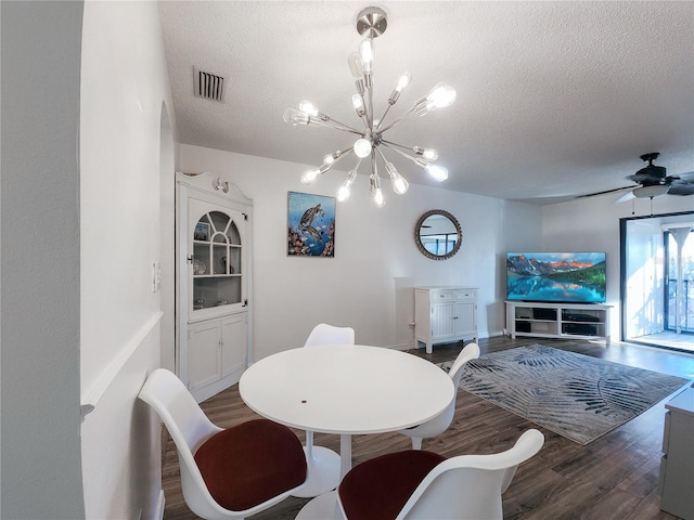 dining area featuring ceiling fan with notable chandelier, dark hardwood / wood-style flooring, and a textured ceiling