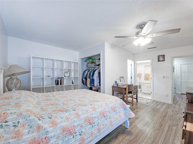 bedroom with ensuite bath, ceiling fan, a textured ceiling, a closet, and hardwood / wood-style flooring