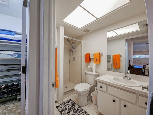 bathroom featuring tile patterned floors, vanity, a shower with shower door, and toilet