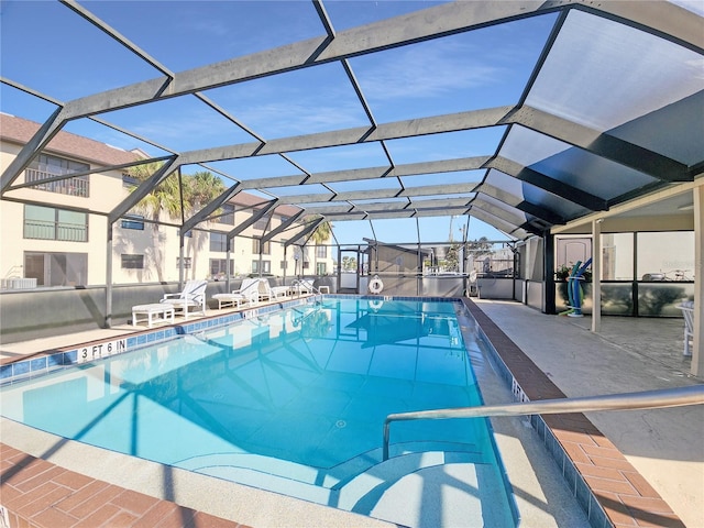 view of pool with glass enclosure and a patio