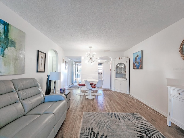 living room featuring light hardwood / wood-style flooring, a textured ceiling, and a notable chandelier