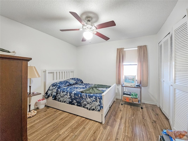 bedroom featuring a textured ceiling, a closet, light hardwood / wood-style flooring, and ceiling fan