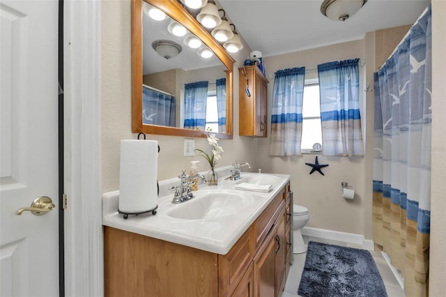 bathroom with tile patterned floors, a wealth of natural light, vanity, and toilet