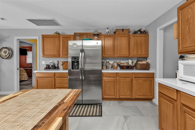 kitchen featuring butcher block counters and stainless steel fridge with ice dispenser