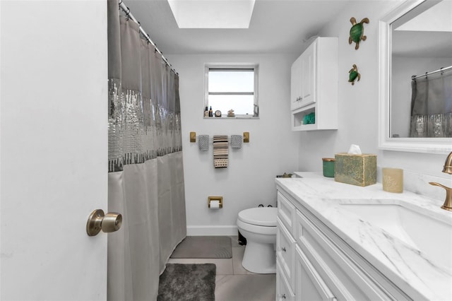 bathroom with tile patterned flooring, vanity, toilet, and a skylight