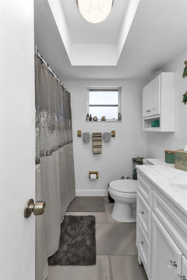 bathroom with vanity, a tray ceiling, toilet, and walk in shower