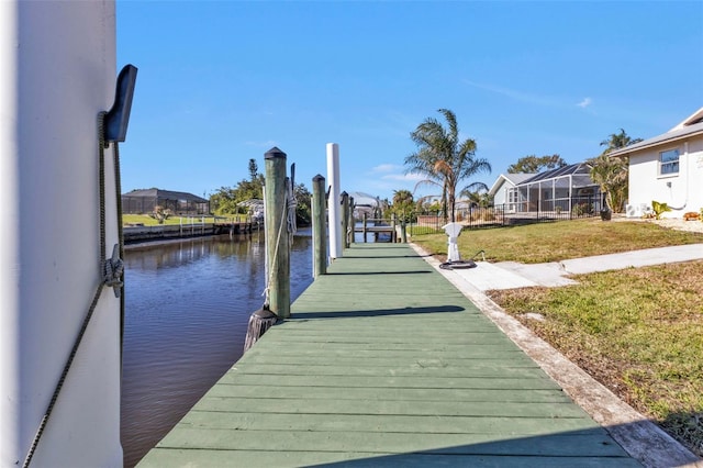 view of dock with a yard and a water view