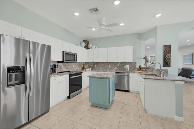 kitchen featuring kitchen peninsula, light stone counters, a kitchen island, and appliances with stainless steel finishes