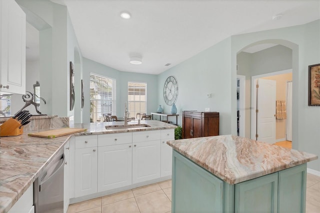 kitchen with a center island, white cabinetry, sink, and light tile patterned floors