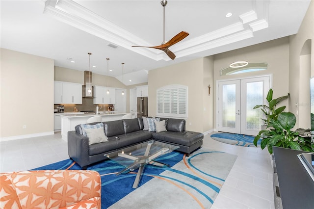 tiled living room featuring ceiling fan, french doors, sink, crown molding, and a tray ceiling