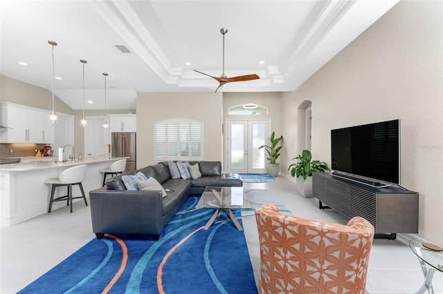 tiled living room with ceiling fan, sink, french doors, a raised ceiling, and ornamental molding