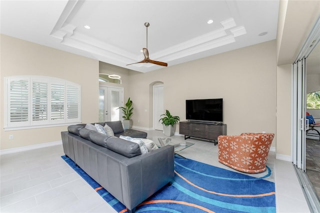 living room featuring a tray ceiling, french doors, and light tile patterned flooring