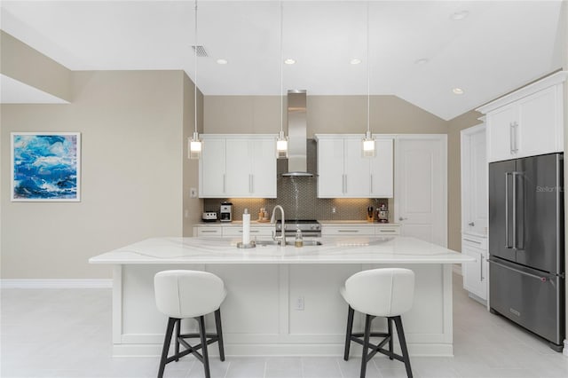 kitchen with a large island with sink, white cabinets, hanging light fixtures, sink, and high end fridge