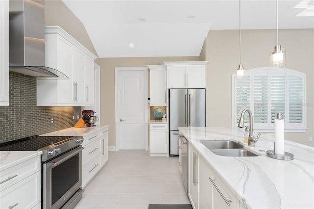 kitchen featuring lofted ceiling, wall chimney range hood, decorative light fixtures, white cabinetry, and stainless steel appliances