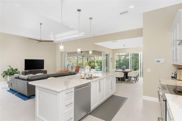 kitchen featuring appliances with stainless steel finishes, a kitchen island with sink, sink, decorative light fixtures, and white cabinetry