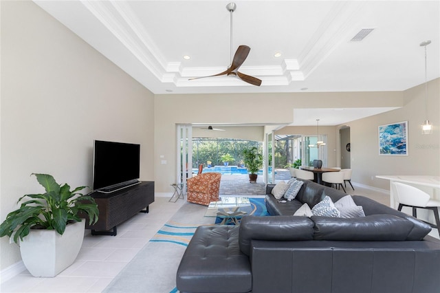 living room featuring a raised ceiling, ceiling fan, light tile patterned flooring, and ornamental molding