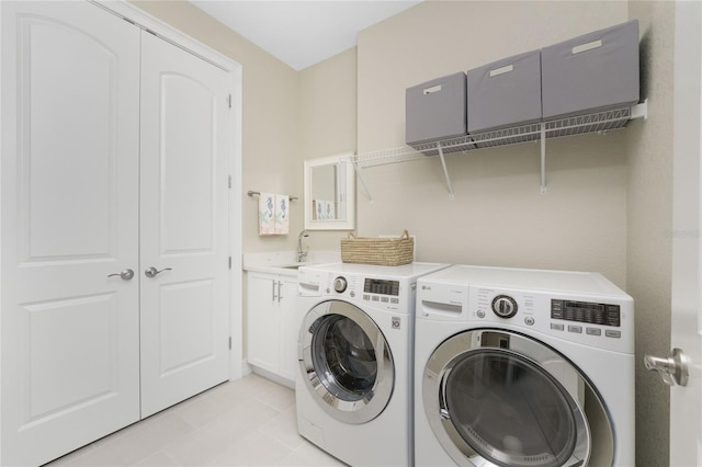 laundry area featuring washer and clothes dryer, cabinets, light tile patterned floors, and sink