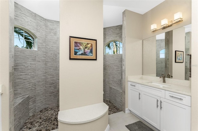 bathroom featuring tile patterned floors, a wealth of natural light, vanity, and tiled shower