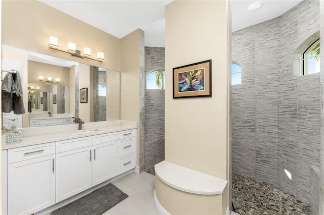 bathroom with tiled shower and vanity