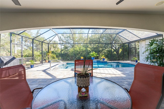 view of swimming pool featuring glass enclosure, ceiling fan, and a patio