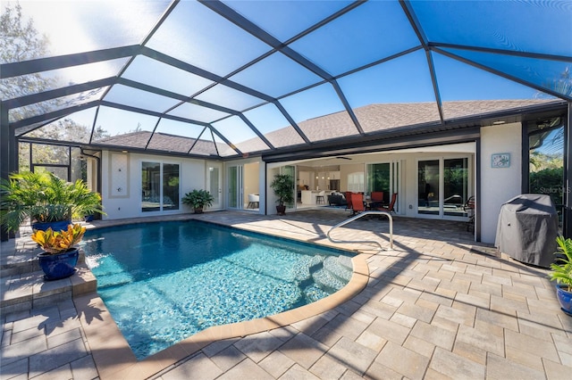 view of swimming pool with area for grilling, a patio, glass enclosure, and ceiling fan