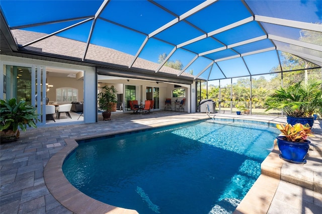 view of swimming pool with ceiling fan, a patio area, and glass enclosure