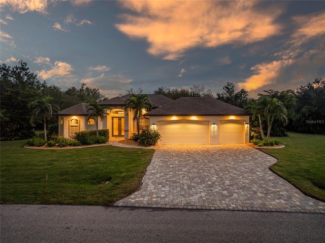 view of front of home with french doors, a yard, and a garage