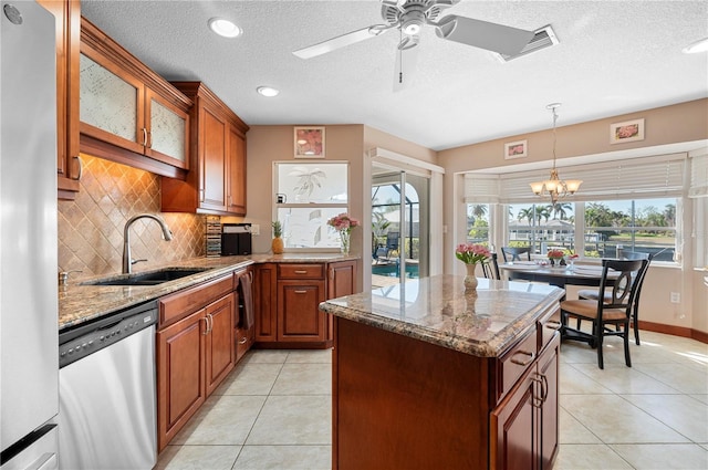 kitchen featuring ceiling fan with notable chandelier, appliances with stainless steel finishes, sink, light tile patterned flooring, and light stone counters