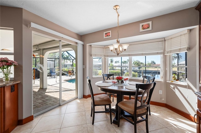 tiled dining space featuring plenty of natural light, a textured ceiling, and a chandelier