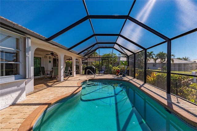 view of swimming pool with ceiling fan, a lanai, and a patio area